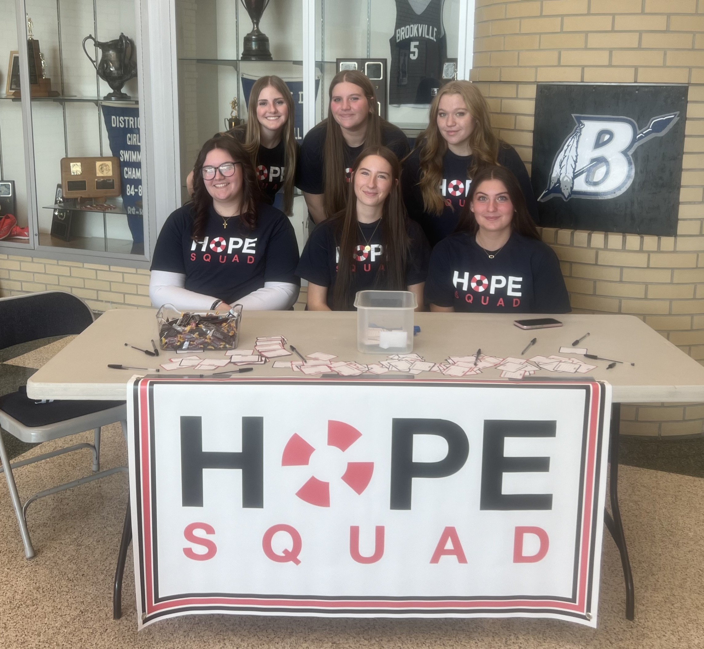 Hope Squad posing behind a table with a large Hope Squad sign.